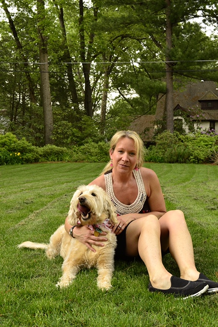 Jenn Meara sitting in the grass with a client's dog